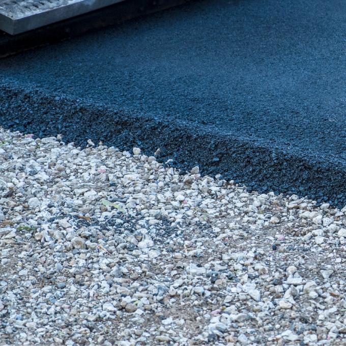 service-img-1 Close-up of freshly laid asphalt adjacent to a gravel surface.